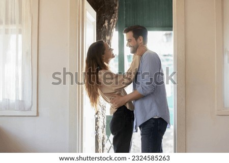 Happy houseowners. Affectionate loving young woman wife hugging embracing smiling millennial man husband lover spouse meeting or seeing off at the door of new rented purchased house apartment dwelling
