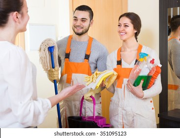 Happy Housewife Meeting Smiling Cleaning Crew At Apartment Doorway
