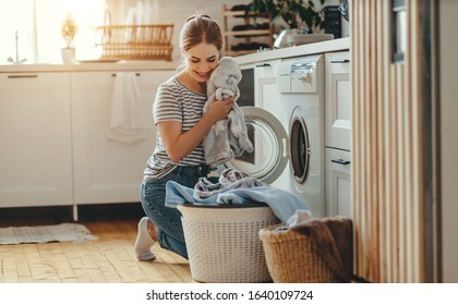 A Happy Housewife Woman In Laundry Room With Washing Machine