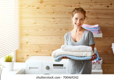 A Happy Housewife Woman In Laundry Room With Washing Machine  
