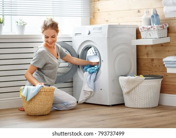A Happy Housewife Woman In Laundry Room With Washing Machine  
