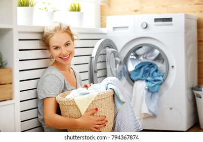 A Happy Housewife Woman In Laundry Room With Washing Machine  
