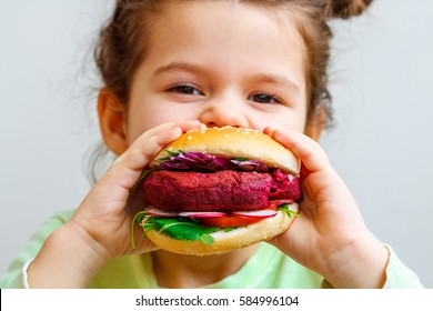 Happy Hungry Child (girl) Eating Healthy Vegan Burger.