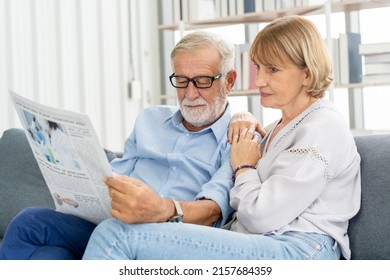 Happy Husband And Wife Senior Couple Elderly Family, Caucasians Mature, Adult Lover And Retired Man, Woman Reading Newspaper,  Report On Sofa Together At Home. Husband And Wife Lifestyle.