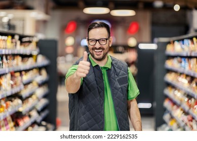 A happy hypermarket manager is standing at marketplace and showing thumbs up at the camera and smiling.