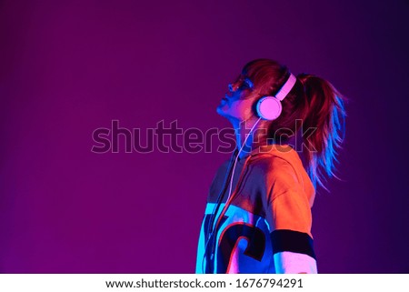 Happy igen teen hipster pretty fashion girl model wear stylish glasses headphones enjoy listen new cool music mix stand at purple studio background in trendy 80s 90s club party light, profile view Stock photo © 