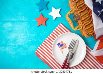 Happy Independence Day, 4th Of July Celebration Concept With Picnic Basket, Plate And USA Flag On Wooden Background. Top View From Above