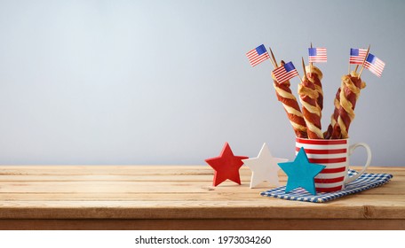 Happy Independence Day, 4th Of July Celebration Concept With Twisted Hot Dog Sausages And USA Flag On Wooden Table