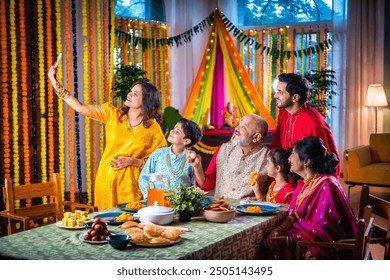 Happy Indian Asian family in festive cloths celebrating hindu festival having dinner, decorated home - Powered by Shutterstock