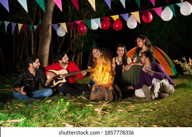 Happy Indian Asian Friends Playing Music And Enjoying Bonfire Or Campfire In Nature