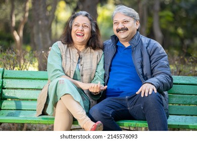 Happy Indian Or Asian Old Couple Talking Laughing While Sitting On The Bench, Senior Man And Woman Relaxing At Park Spend Time Together, Relationship And People Concept.