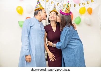 Happy Indian Asian Old Couple Celebrate Birthday. Elderly Retired People And Young Doing Party Together. Father Mother Kiss Hug Daughter