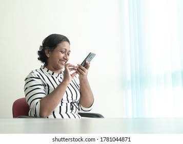 Happy Indian Businesswoman Leave A Voice Message On Her Cellphone. Office Setting.