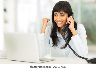 happy indian businesswoman receiving exciting news over the phone