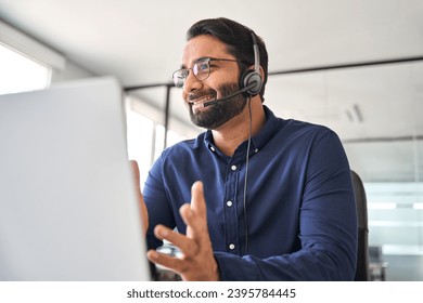 Happy Indian call center agent wearing headset talking to client working in customer support office. Professional contract service telemarketing operator using laptop having conversation. Candid shot - Powered by Shutterstock