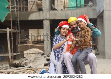 Happy Indian construction manager in uniform wishing merry Christmas and happy new year to kids wearing Santa Claus Cap. Kids waiting for their dream home and making a house metaphor from hands.