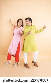 Happy indian couple dancing together wearing traditional or ethnic cloths isolated on studio background, Man and woman celebrating diwali festival, onlie sale, enjoying life concept, - Shutterstock ID 2204098389