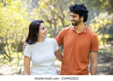 Happy indian couple laughing while looking at each other in the park, cheerful urban city man and woman wearing casual t-shirt having fun together, husband wife morning walk outdoor. - Powered by Shutterstock