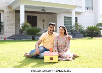 Happy Indian Couple With Model House At Farmhouse