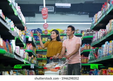 Happy Indian couple pointing while shopping at grocery store