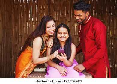 Happy Indian Family With A 10 Year Old Daughter Using Mobile Phone Together