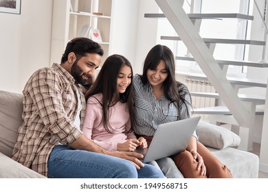 Happy indian family couple with child daughter using laptop computer at home. Smiling parents and teen kid bonding watching streaming online tv or doing ecommerce shopping together sitting on sofa.