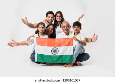 Happy Indian family holding national tricolour flag while sitting isolated over white background, selective focus