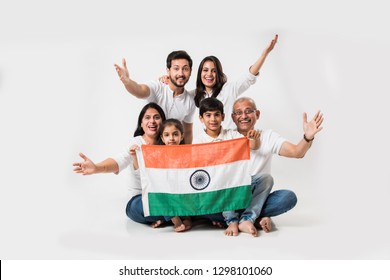 Happy Indian family holding national tricolour flag while sitting isolated over white background, selective focus