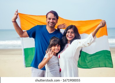 Happy Indian family holding national tricolour flag on beach Goa - Powered by Shutterstock