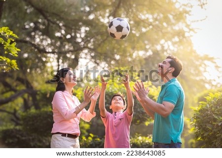 Happy indian family playing with football at park