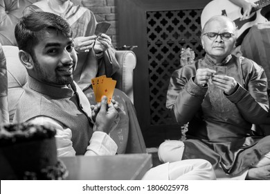 Happy Indian Family Playing Teen Patti Or Three Cards Game On Diwali Festival Night In Traditional Wear At Home