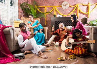Happy Indian Family Playing Teen Patti Or Three Cards Game On Diwali Festival Night In Traditional Wear At Home