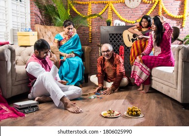 Happy Indian Family Playing Teen Patti Or Three Cards Game On Diwali Festival Night In Traditional Wear At Home