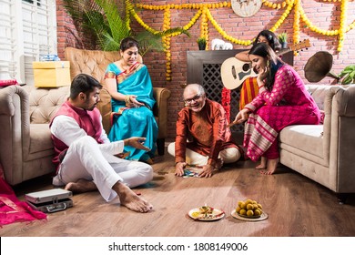 Happy Indian Family Playing Teen Patti Or Three Cards Game On Diwali Festival Night In Traditional Wear At Home