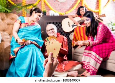 Happy Indian Family Playing Teen Patti Or Three Cards Game On Diwali Festival Night In Traditional Wear At Home