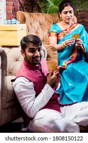 Happy Indian Family Playing Teen Patti Or Three Cards Game On Diwali Festival Night In Traditional Wear At Home