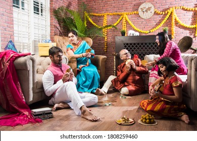 Happy Indian Family Playing Teen Patti Or Three Cards Game On Diwali Festival Night In Traditional Wear At Home