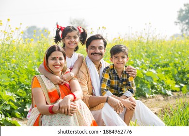 Happy Indian family standing in mustard agricultural field