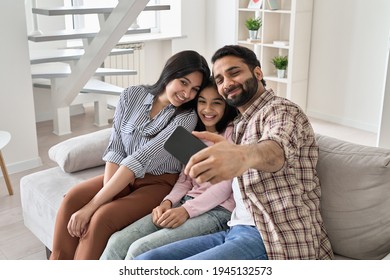 Happy Indian Family With Teen Child Daughter Having Fun Taking Selfie On Modern Smartphone At Home. Smiling Parents And Teenage Kid Bonding Looking At Mobile Phone Posing For Family Photo Sit On Sofa.