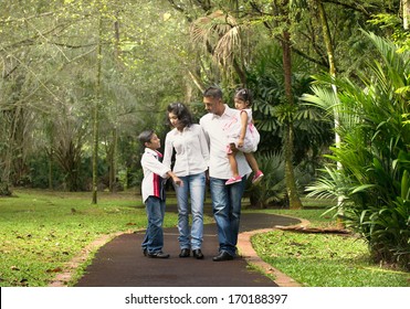 Happy Indian Family Walking Outdoor In The Park