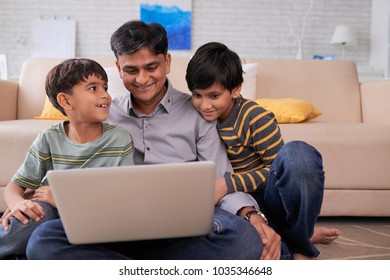 Happy Indian Family Watching Something On Laptop At Home