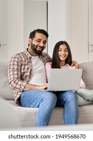 Happy Indian Family Young Father With Teen Child Daughter Having Fun Using Laptop Computer At Home Watching Tv Movie, Browsing Internet, E Learning, Laughing, Sitting On Sofa In Modern Living Room.