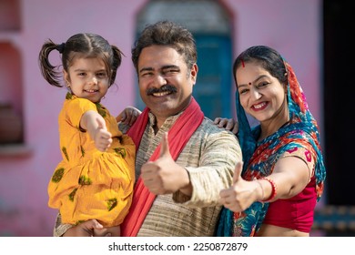 Happy indian farmer couple with little daughter showing thumps up at home. - Shutterstock ID 2250872879