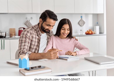 Happy Indian Father Helping School Child Hugging Teen Daughter Studying At Home. Young Dad Explaining Kid Teenage Daughter Learning In Kitchen Together, Doing Homework During Homeschooling Time.