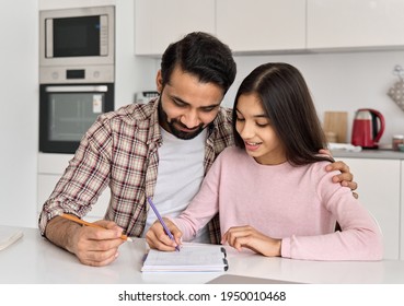 Happy indian father helping school child embracing teen daughter studying at home. Young dad explaining kid teenage daughter learning in kitchen together, doing homework. Parenthood and homeschooling.