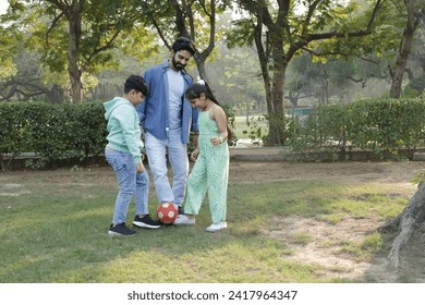 Happy Indian father playing football with kids at park. - Powered by Shutterstock