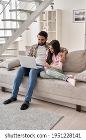 Happy Indian Father And Teen Daughter Using Laptop Computer At Home. Ethnic Family Young Dad With Teenage Child Girl Having Fun Sitting On Couch Watching Tv, Online Learning Browsing Internet Together