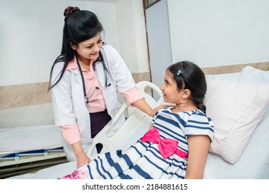 Happy Indian Female Doctor Visit Girl Kid At Hospital Bed. Sick Child At Clinic.