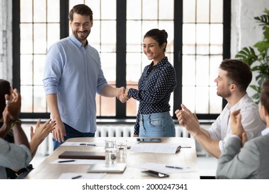 Happy Indian Female Team Leader Shaking Hands With Proud Employee, Thanking Promoted Worker For Good Job And Congratulating With Reward. Millennial Business Group Welcoming Newcomer With Applause