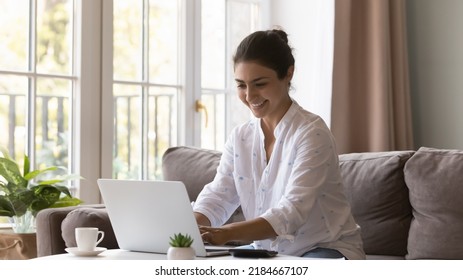 Happy Indian Freelancer Woman Working From Home, Using Laptop Computer, Calculator, Typing, Smiling, Laughing, Chatting Online, Enjoying Business Communication. Renter, Homeowner Using App